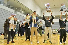 親子レクリエーションで子供を抱き上げる保護者