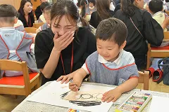 園児と一緒に絵を描く保護者